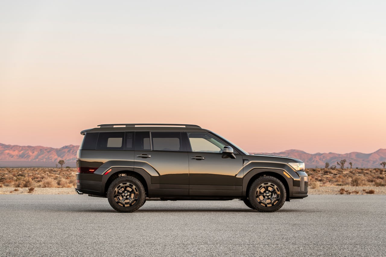 Side view of an SUV parked on a desert road during sunset, showcasing a scenic landscape.